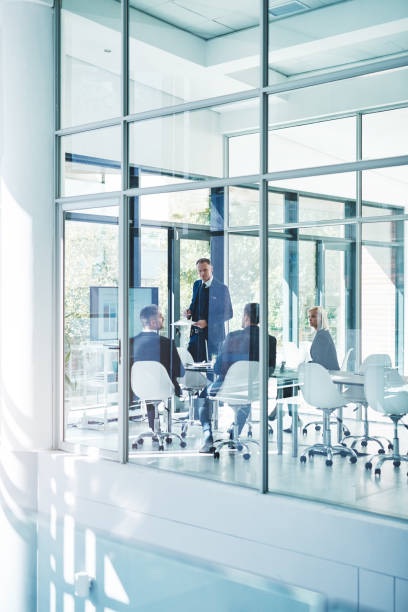 Executives in a glass-walled boardroom, seen from outside